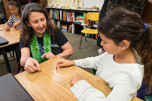 Picture of NASA SSERVI director Yvonne Pendleton using coin faces to help students visualize how the moon rotates as it orbits the Earth