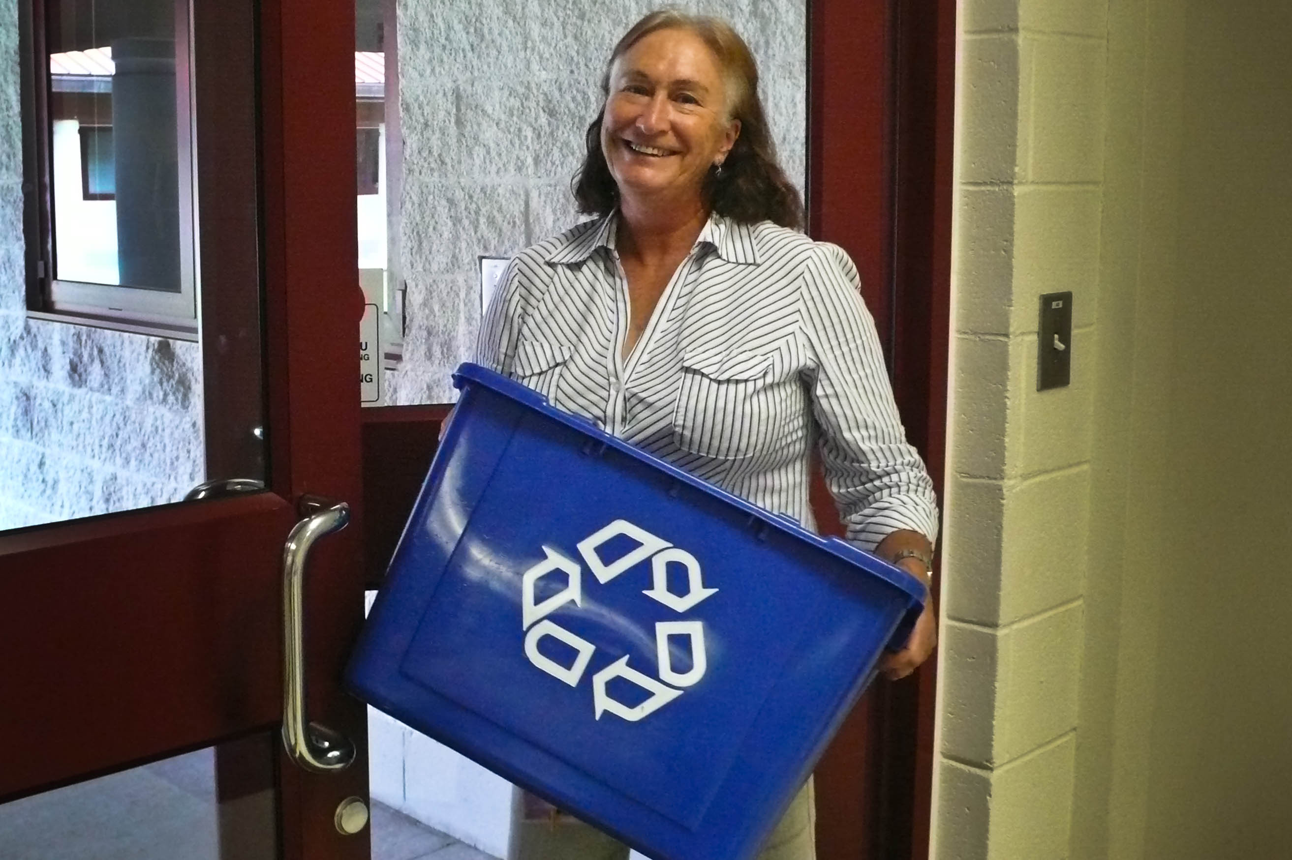 Photo of a member of the staff holding a recycling can.