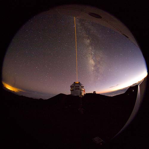Picture of the Gemini North telescope and the laser guide system propagating, taken from the Canada-France-Hawaii telescope.