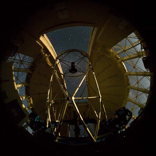 Picture of the Gemini North telescope being illuminated by the moon through the ventilation gates. Milky way is visible in the background.